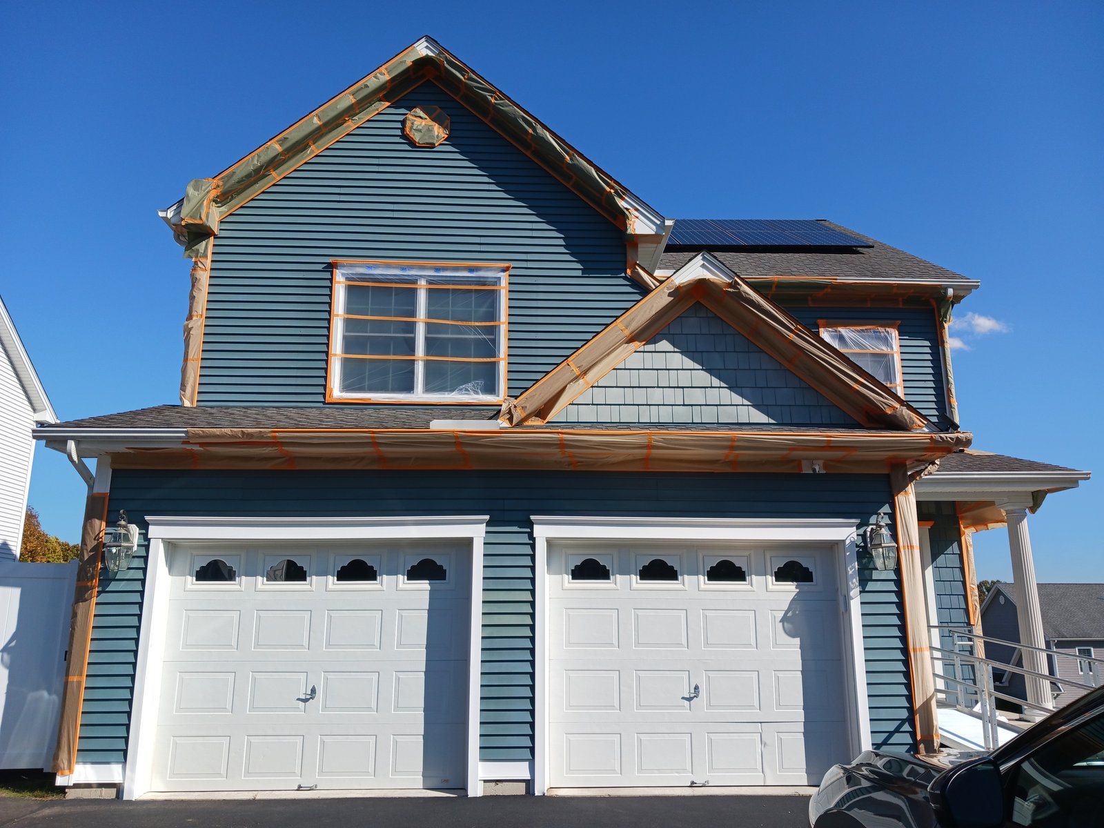 Exterior House Blue Siding White Garage Doors Solar Panels Painting In Progress — Frank Leonard Painting LLC