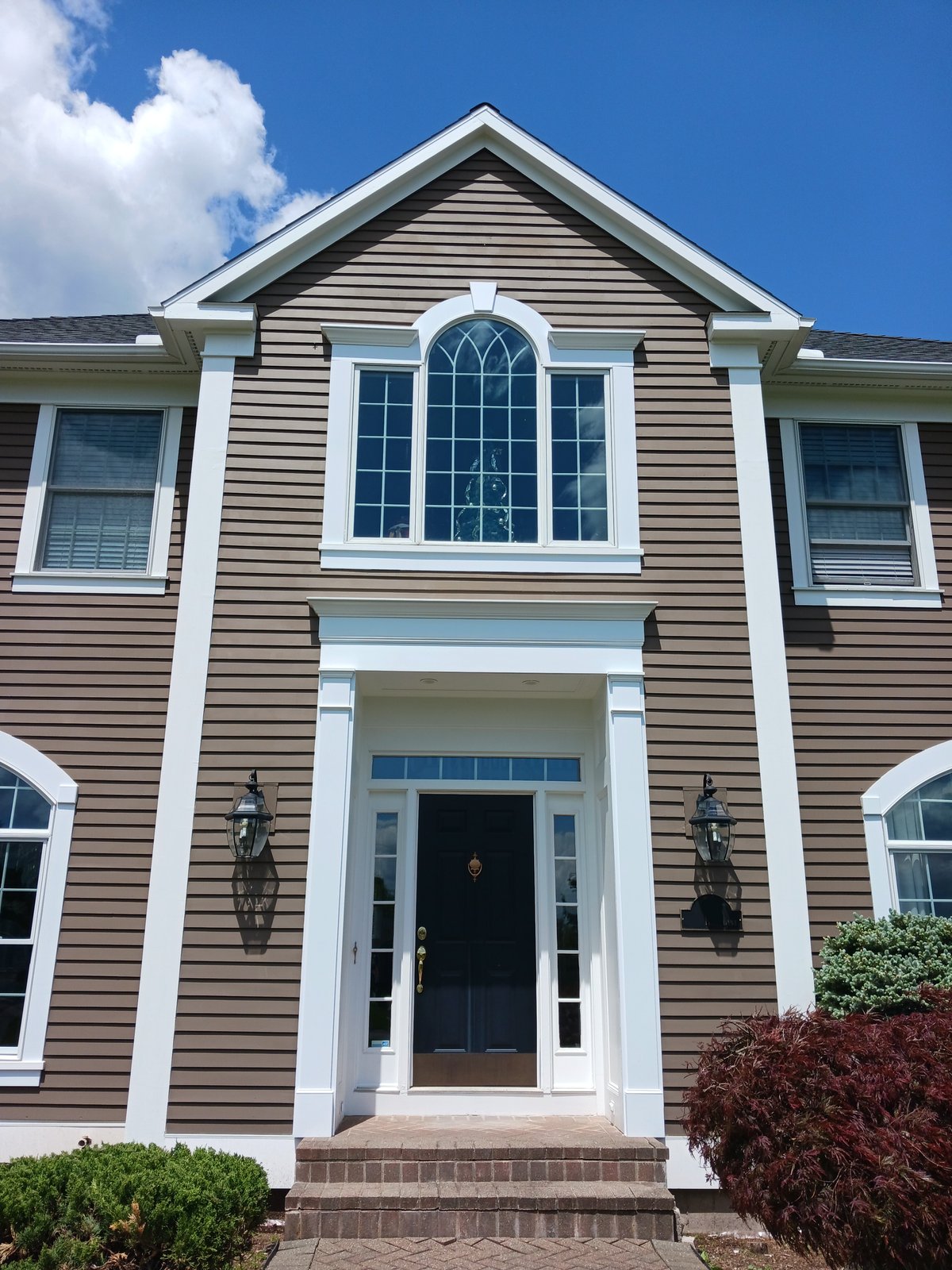 Exterior house — brown siding with white trim and black door