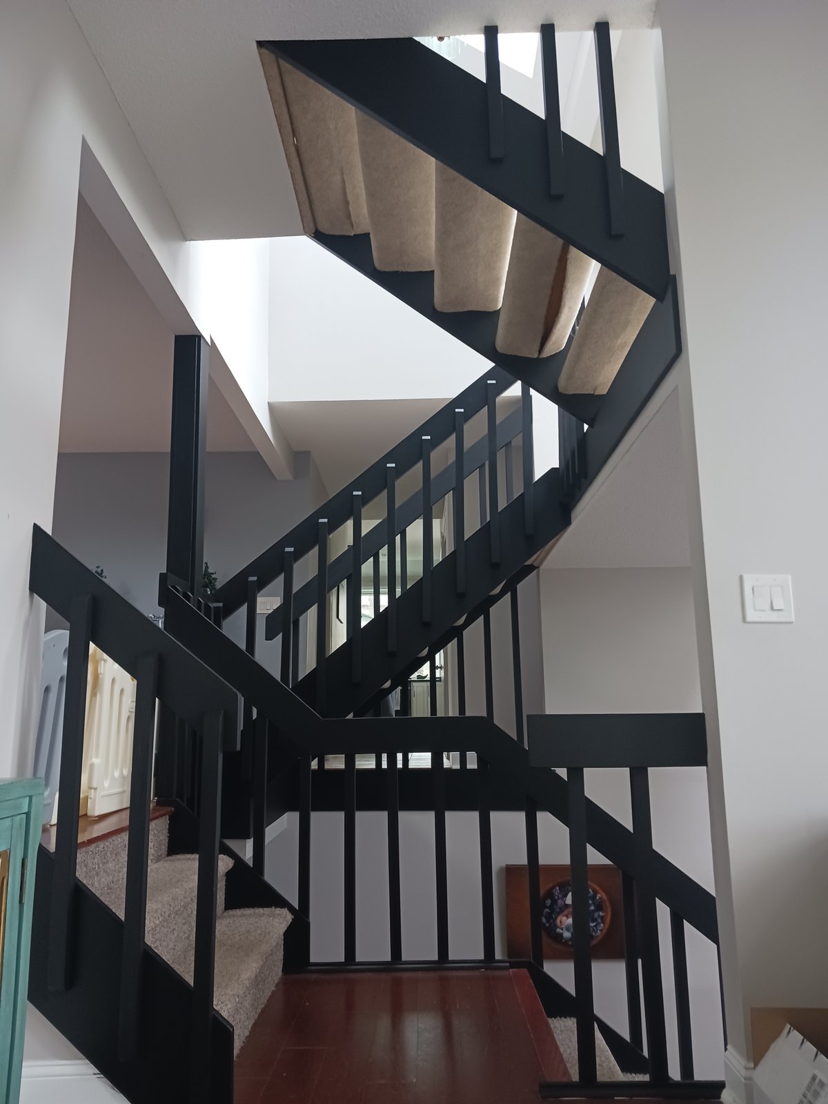 Interior staircase — black railings, light gray walls, hardwood floor
